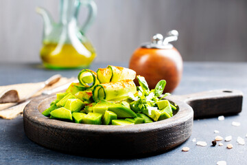 Salad with , avocado, cucumber and nuts on plate, top view