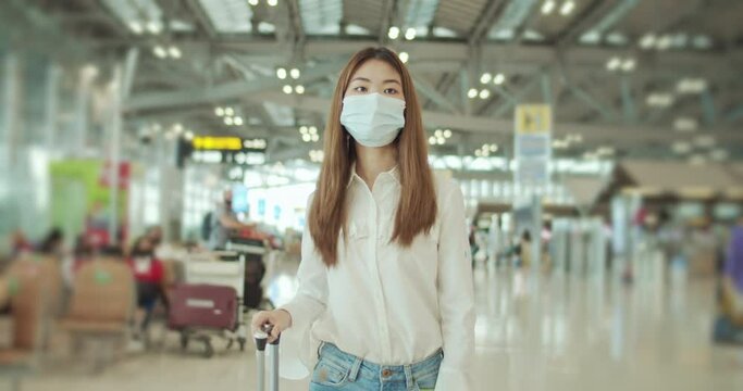 Young traveller woman walking at airport - wearing face mask,Slow motion
