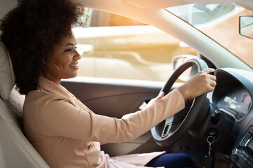 african successful woman driving driving car in suit 