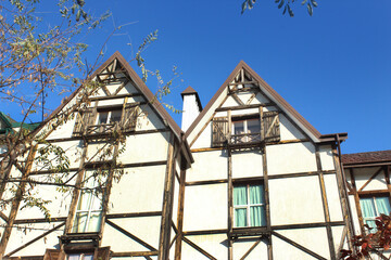 Facade of a black and white half-timbered house in European medieval style with two gabled roofs. Prussian wall with braided wooden beams