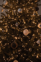 Closeup of Christmas tree decorated with glowing garland lights, baubles