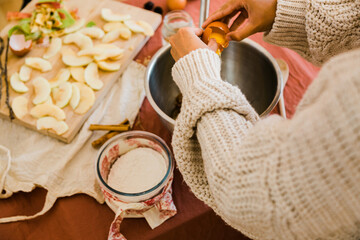woman's hands cracking an egg preparing an apple dessert