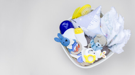 Basket with baby clothes, diapers, rattles and toys on background with copy space