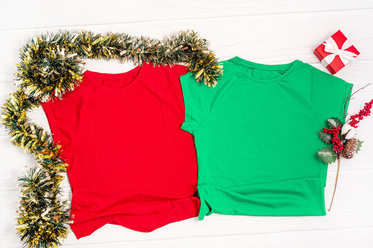 Red and green t shirt mockup with copy space and Christmas Holiday template flatlay. Top view blank t-shirt on white background. Happy New Year decorations