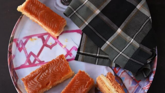 A hand taking traditional Colombian dessert Milhojas with tongs