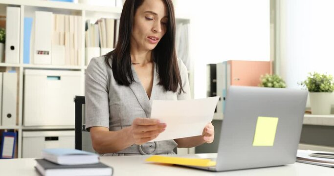 Woman opening envelope with letter and grabbing her head in office 4k movie