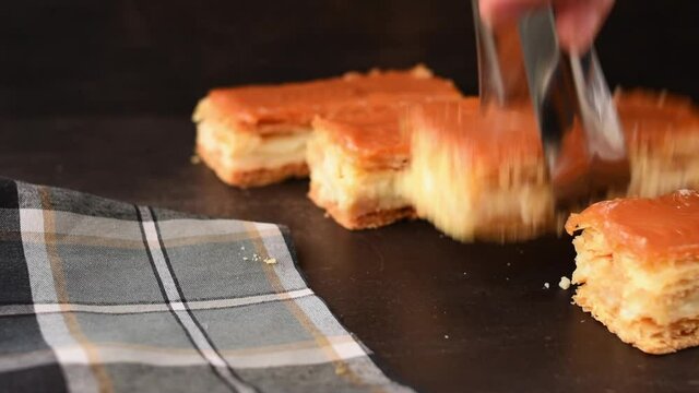 A hand taking traditional Colombian dessert Milhojas with tongs