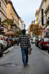 man walking in the street holding a skateboard