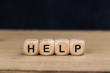 Wooden cube with the word HELP on wooden table.