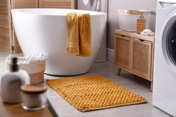 Soft orange mat on floor near tub in bathroom. Interior design