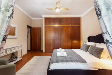 Bedroom in classic traditional Mediterranean style with double bed. With a mirror, and towels with sweets on the bed.