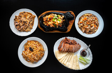 Group of different Asian dishes of baked Peking duck, Chow Mein noodles in iron pan, shrimp with vegetables. chicken stew almonds, carrots and pasta. Flat lay .