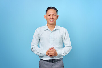 Smiling young handsome businessman holding hands with a confident face on blue background