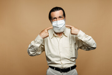 European senior man pointing fingers at his face mask