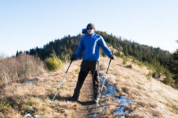 Hiker man with trekking poles stay in the forest