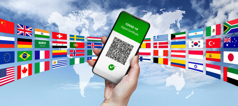 Green pass covid-19 vaccination concept. Hand holds smartphone with qr code digital vaccine certificate on screen. isolated on blue sky with international flags and world map background.