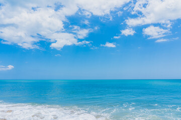 Turquoise water on the Atlantic Ocean beach merges with the blue sky with white clouds in Florida