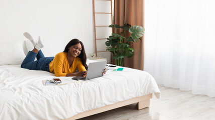 Obraz premium Black Woman Using Laptop Lying In Bed At Home, Panorama