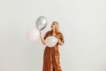 Happy young beautiful blonde woman posing with balloons over white background. Holiday concept, birthday, new year, christmas