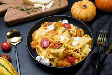 Italian  pasta pappardelle with pumpkin, tomatoes and mozzarella. vegetarian food