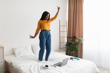 Happy African Woman Listening Music On Laptop Dancing In Bedroom