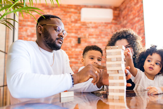 African Mixed Race Family Palying A Round Of Jenga In Cozy Living Room With Air Conditioning