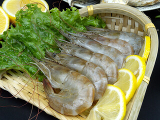 Close-up of prawns and lemon in a bamboo dustpan, ingredients