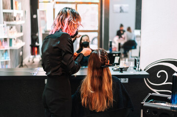 Woman hairdresser making braids to client
