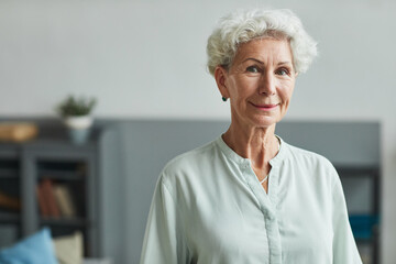 Portrait of smiling senior woman looking at camera in retirement home, copy space