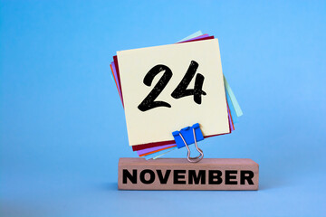 November 24th. Day 24 of November month, calendar on workplace with blue background. Autumn time.
