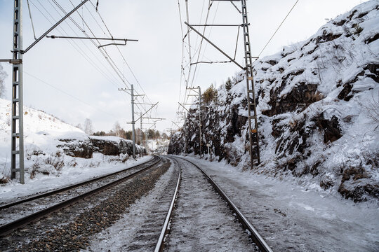 The railway goes through the rocks. Snow-covered iron dorga. Soota from a steam locomotive in the snow in winter. Rails in the snow