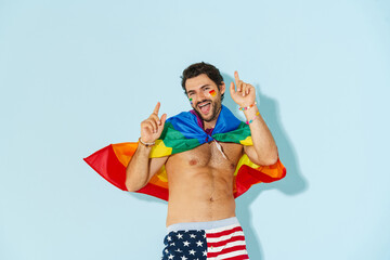 Young man with rainbow flag dancing while pointing finger upward