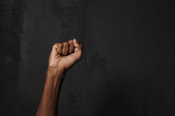 Black man's hand clenching fist isolated over dark background