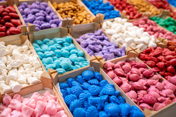 Handmade soaps in different shapes and colours in wooden boxes for sale. Cute colorful little organic animal shaped soap bars for kids. Selective focus.