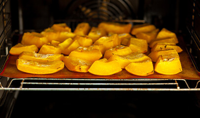 Pumpkin slices baked on a baking sheet in the oven. Homemade food, Vegan food, Healthy food, orange vegetables on a baking sheet and napkin, baked rustic vegetables, pop art, dessert during a diet