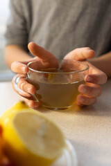 child hands holding a cup of tea near of a plate with berries and citrus. The concept of natural teas, maintenance of immunity, antioxidants, vitamin c. Vertical