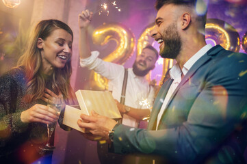 Happy couple celebrate New Year's Eve with their friends and exchanging gifts