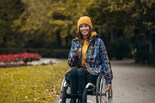 Woman in wheelchair using a smartphone while out in the city park