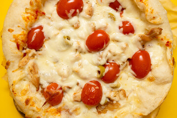 Appetizing homemade pizza Margarita with cheese and tomatoes on a yellow background with copyspace