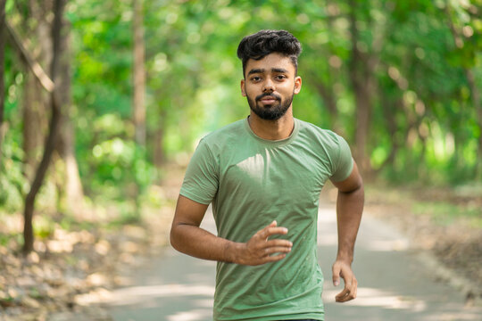 Young Man Running In The Park At Morning, Also Known As Jogging Or Morning Walk