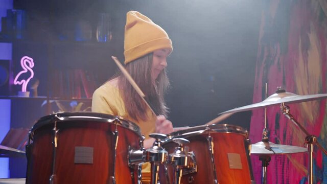 Drummer. Waist up portrait view of the young woman sitting at the hi hat drum kit and aggressively playing at the repetition