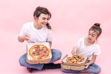 Funny girls with pizza in boxes for delivery on a pink background.