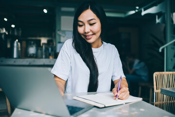 Fototapeta na wymiar Positive Asian female freelancer surfing laptop