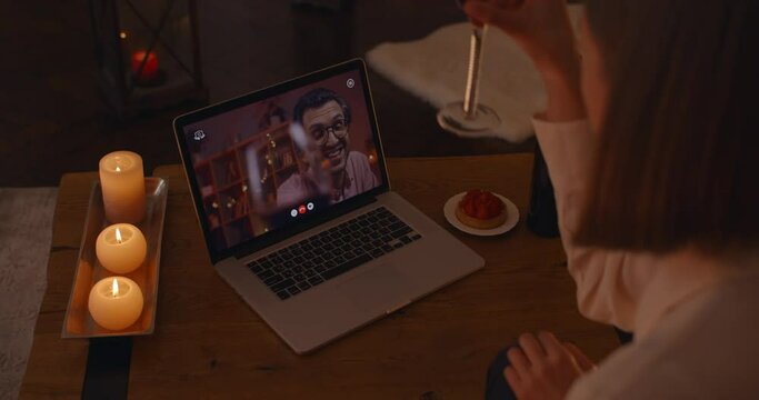 Happy couple drinking wine and talking druing video call