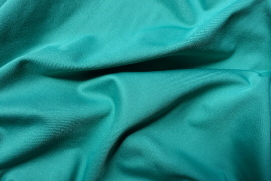 Bright blue green polyester fabric in soft folds