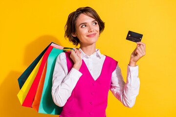Photo of dreamy sweet young lady wear pink suit holding bargains bank card looking empty space isolated yellow color background