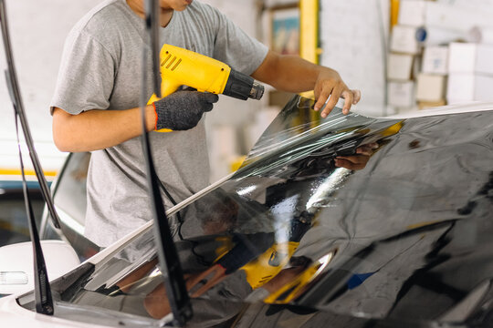 Car specialist tinting film for car glass with hairdryer.