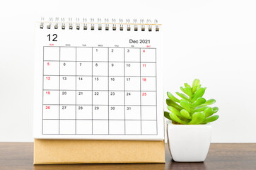 December 2021 desk calendar on wooden table.