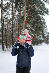 Fototapeta na wymiar Portrait of happy father and baby toddler daughter on winter nature background. Man and baby girl on his shoulders in winter park. Christmas holidays, Family vacation in winter forest.