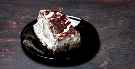 Plate with slice of tasty chocolate cake on table. Yummy dessert on on wooden background, closeup